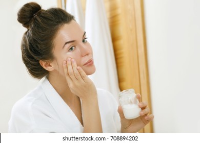 Woman is moisturizing her skin with a coconut oil - Shutterstock ID 708894202