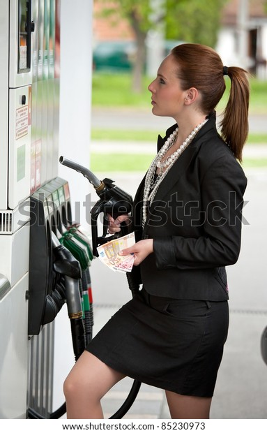 woman with money\
at gas station holding\
nozzle