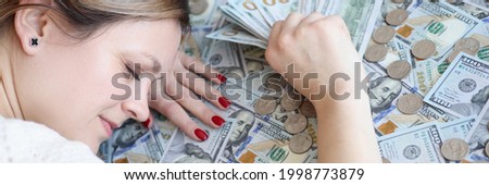 Woman with money in her hands sleeping on dollar bills