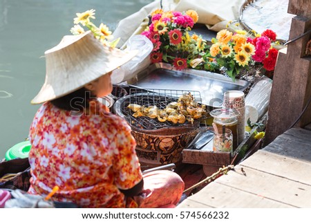 Woman monger is selling grilled squid at Pattaya Floating market