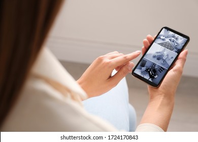 Woman monitoring modern cctv cameras on smartphone indoors, closeup. Home security system