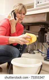 Woman Mopping Up Leaking Sink On Phone To Plumber