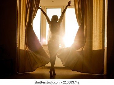 Woman in the morning. Attractive sexy woman with slender body is looking at the sunrise standing near the window in her home and having a perfect cozy morning. 