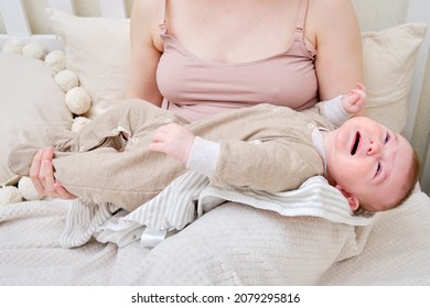 A Woman Mother Breastfeeding A Crying Infant Baby With A Phone In Her Hand. Mom Problems With Breastfeeding And Finding A Solution On The Internet