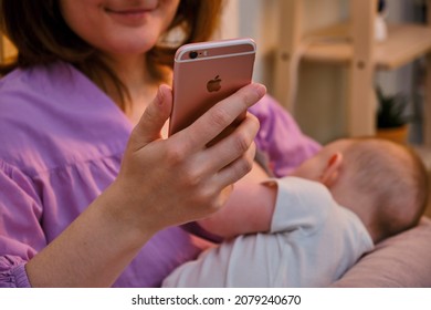 Woman Mother Breastfeeding Infant Baby With IPhone Apple - Moscow, Russia, November 15, 2021