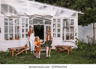 Woman mother and two red-haired daughter girls care and plant plants in pots in a greenhouse, doing gardening in the spring for Earth Day. - Powered by Shutterstock