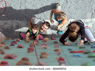 Woman Mother in white shirt and green pants and her son boy climbing vertical wall together - Powered by Shutterstock