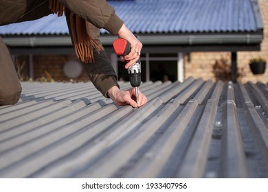 Woman Mounting Old Trapezoidal Metal Roof Using A Power Drill. Close Up Image.