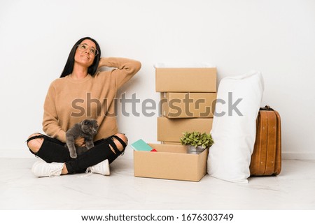 Woman moving home isolated on white background touching back of head, thinking and making a choice.