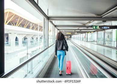 Woman In The Moving Walkway At The Airport With A Pink Suitcase.