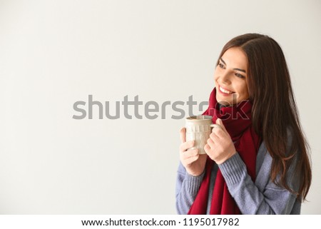 Woman with mug of delicious mulled wine on light background