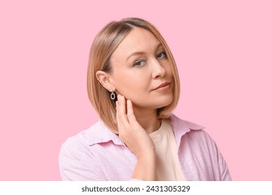 Woman with multiple ear piercing on pink background