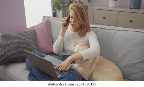 A woman multitasks by talking on the phone and using a laptop with her dog beside her on a couch in a cozy living room. - Powered by Shutterstock