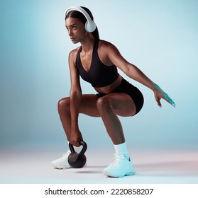 Woman, music and fitness stretching with kettlebell in blue background studio. Young female athlete, workout training with equipment and focused sport wellness with audio motivation on headphones - Powered by Shutterstock