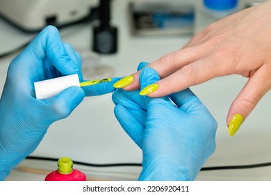 Woman nail master doing nails to girl client at beauty salon. Master manicurist applies pistachio bright gel nail polish on client nails - Shutterstock ID 2206920411