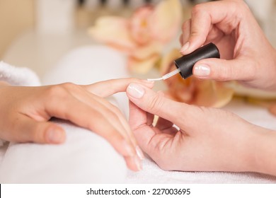 Woman in nail salon receiving manicure by beautician. closeup of female hand resting on white towel - Powered by Shutterstock