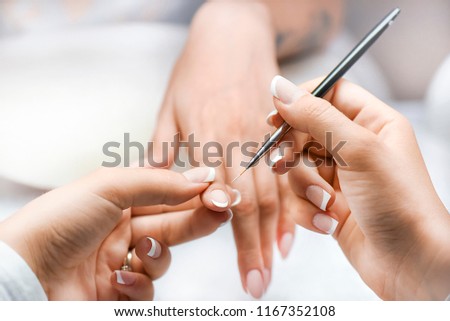 Woman nails manicure close up. Nail profi paint white color or french with thin brush.