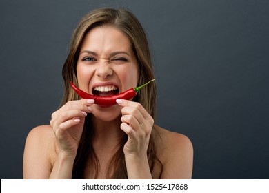 Woman With Naked Shoulders Eating Red Hot Chilli Peppers. Isolated Portrait On Dark Gray.