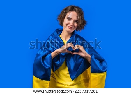 Woman with national Ukrainian flag showing sign of shape heart on yellow.Volunteering, charity donation, gratitude symbol,. High quality photo
