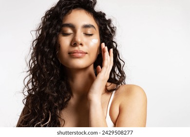 mujer con maquillaje natural disfruta aplicando crema en su cara