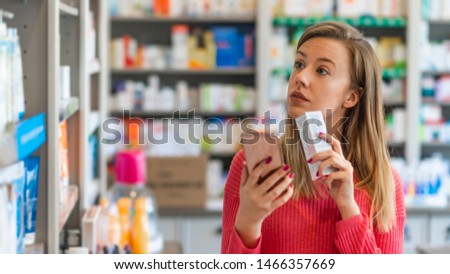 Woman near counter in pharmacy drugstore. Happy to decide. Portrait of a happy pharmacy client holding a medication product. Young woman choosing cosmetic cream in beauty shop.