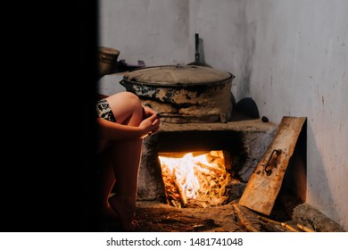 A Woman Near An Old Primitive Wood Oven Indoors.