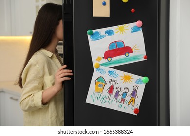 Woman near refrigerator with child's drawings in kitchen, closeup - Powered by Shutterstock