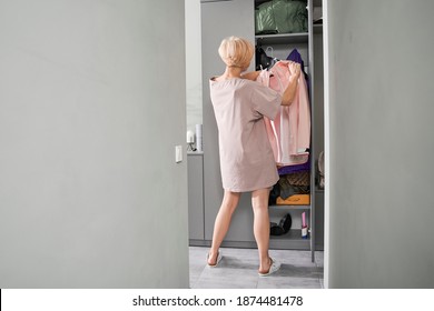 Woman Near Wardrobe For Cloths With Clothes On A Hanger. Girl Trying Clothing. Closet With Bags, Boxes And Shoes. Stock Photo