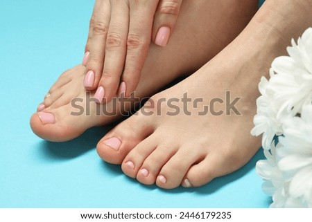 Woman with neat toenails after pedicure procedure on light blue background, closeup