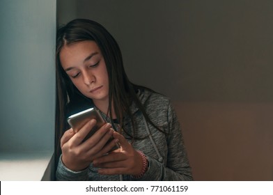 Woman With Negative Surprised Face Looking Something In Smartphone. Sad Teenager With Mobile Phone, Scared Of Threatening, Mobile Abuse. Front View Of A Sad Teen Checking Phone 