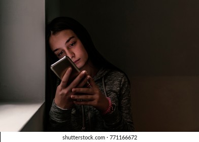 Woman With Negative Surprised Face Looking Something In Smartphone. Sad Teenager With Mobile Phone. Front View Of A Sad Teen Checking Phone Sitting On The Floor In The Living Room At Home.