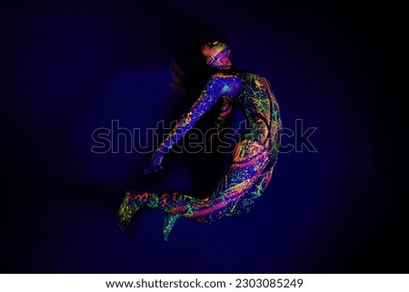Woman, neon paint and dancer jump on dark background for creative performance, splatter texture and psychedelic fantasy. Body artist, color splash and unique glow in surreal circus on mockup studio