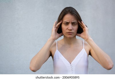 Woman In Nervous Stress With Headache. Dull Headache. Hands At The Temples. Senses Concept