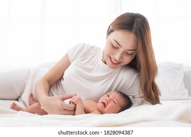 Woman And New Born Boy Relax. Mother Breast Feeding Baby. Family At Home. Happy Mother And Baby. Young Mother Holding Her Newborn Child. Mom Nursing Baby. Mother And Baby Child On A White Bed.