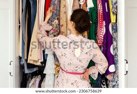 A woman in a new dress is standing in front of her closet trying to figure out what to wear. Fast fashion concept.
