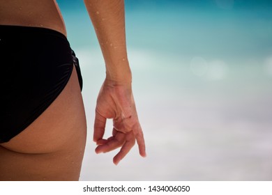 Woman with nice butt in black bikini showing ok-sign with caribbean beach background - Shutterstock ID 1434006050