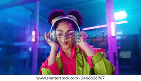 Woman, night and headphones for music, glasses and dancing for motivation in office. Happy female person, hip hop playlist and movement in neon light, connection and streaming radio while working