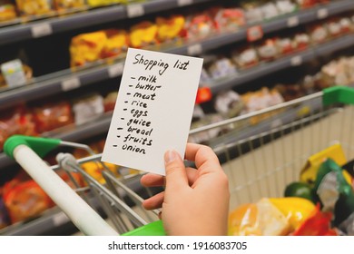 Woman with notebook in grocery store, closeup. Shopping list on paper. Check purchases in grocery cart.