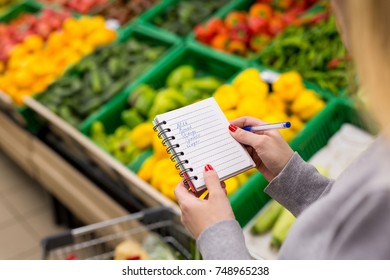 Woman With Notebook In Grocery Store, Closeup. Shopping List On Paper.