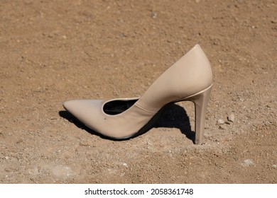 Woman nude heel sitting on baseball or softball field near chalk line in dirt 