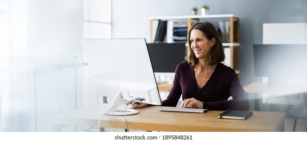 Woman In Office Using Business Computer At Desk