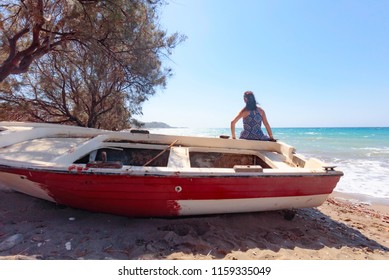 Woman And Old Fishing Boat On A Beach Of The Mediterranean Sea.