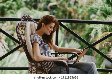 woman on the balcony with a laptop in her hands and nature in the background freelancer - Powered by Shutterstock