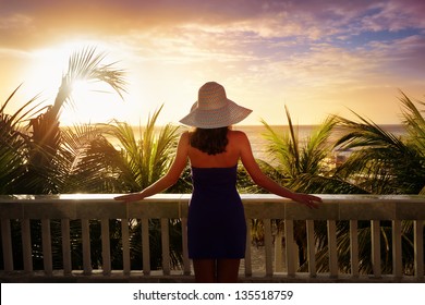 A woman on a balcony looking at the beautiful Caribbean sunset.