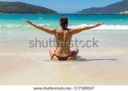Woman on the beach looking out to sea and meditating.