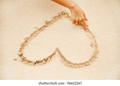 Woman On The Beach Making Heart On The Sand