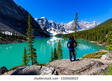 Woman on cliff admiring Moraine Lake and mountains scenic view, Rocky Mountains, Banff National Park, Alberta, Canada - Powered by Shutterstock