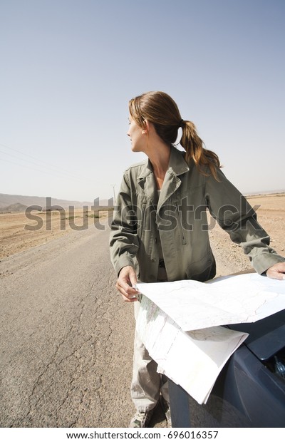 Woman on a deserted\
road with a road map