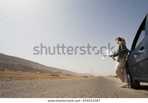 Woman on a deserted\
road with a road map