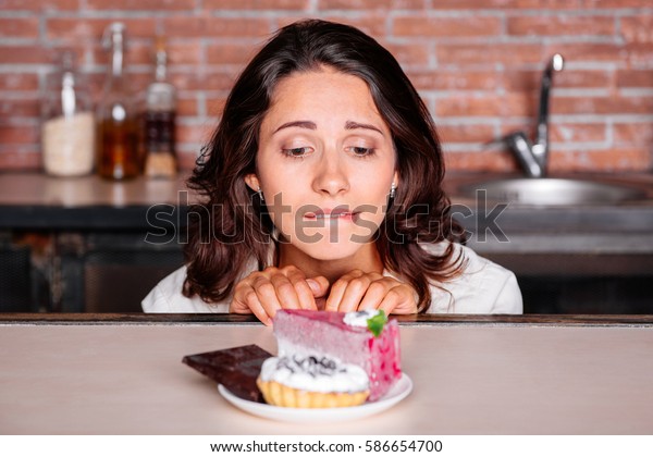 Woman on the\
diet craving to eat cake.  Young attractive woman really wants to\
eat delicious cake. diet\
concept